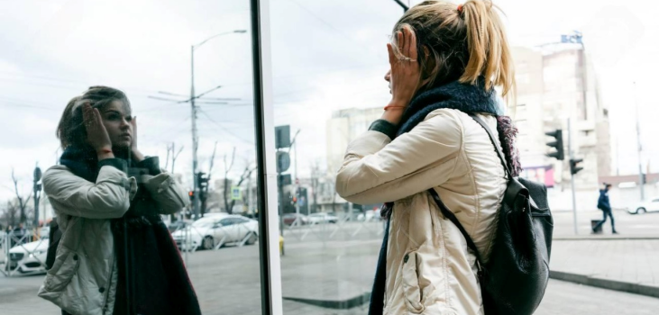 Woman seeing her reflection at a store window and pulling her face skin back