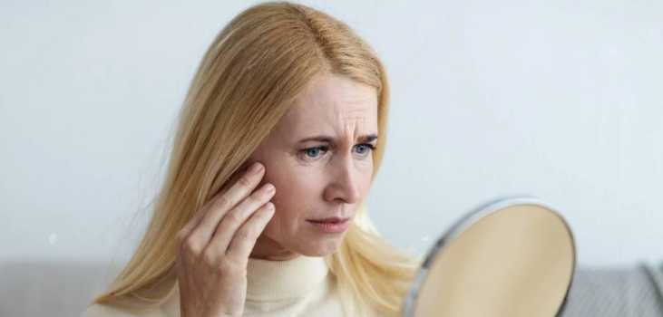 Mature woman looking at her wrinkles in a mirror