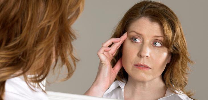 Mature woman looking at her wrinkles in a mirror